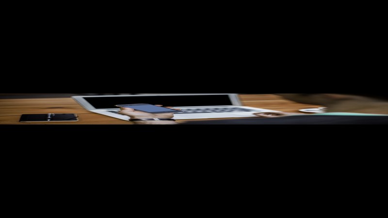 A person working on a smartphone and laptop — AppLovin's CEO pay is equity-heavy, tied to the company's ad-tech performance